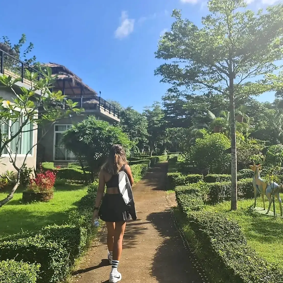 Player walking through a lush tropical garden path to the tennis courts on Koh Mak